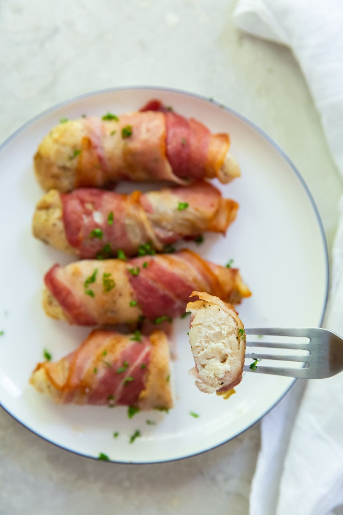 Bacon wrapped chicken tenders one piece cut with a fork in it.