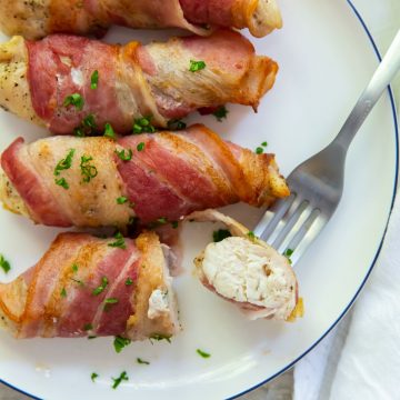 Bacon wrapped chicken tenders one piece cut with a fork in it.