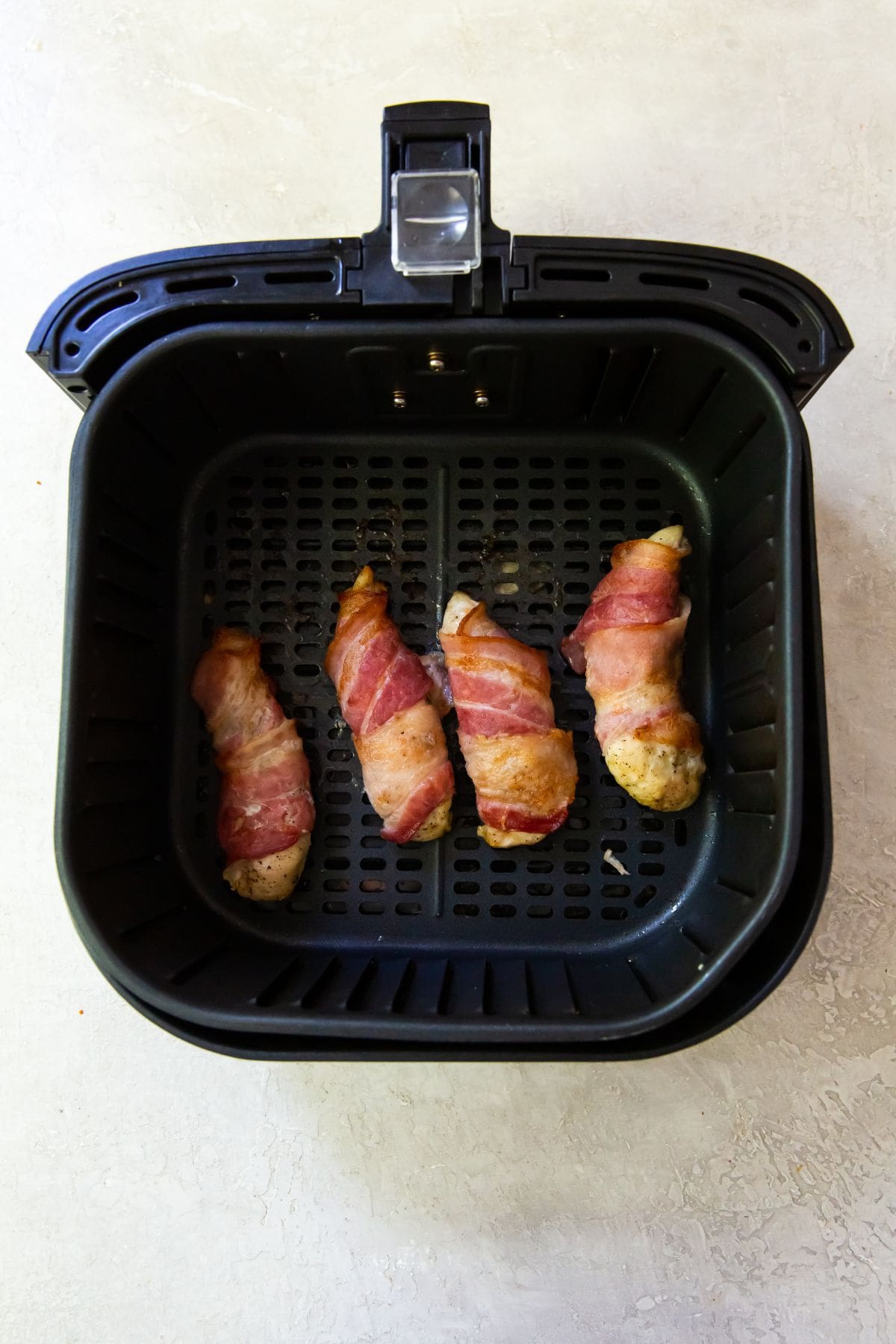 Black Air Fryer with cooked bacon wrapped chicken tenders