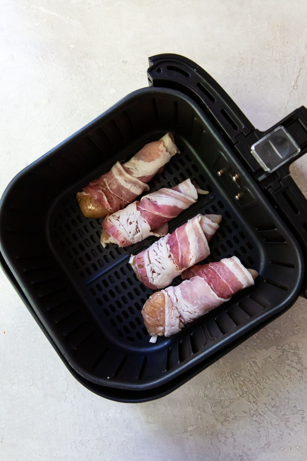 Black Air Fryer with bacon wrapped chicken tenders.