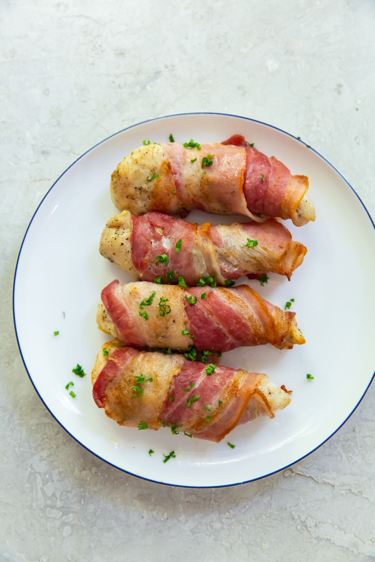 bacon wrapped chicken tenders on a white plate.