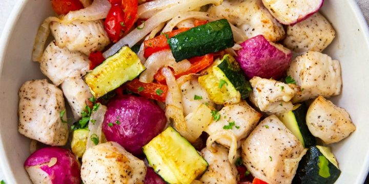 White bowl with chicken and veggies inside it. Gray towel on side