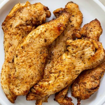 White plate full of cooked chicken breast strips