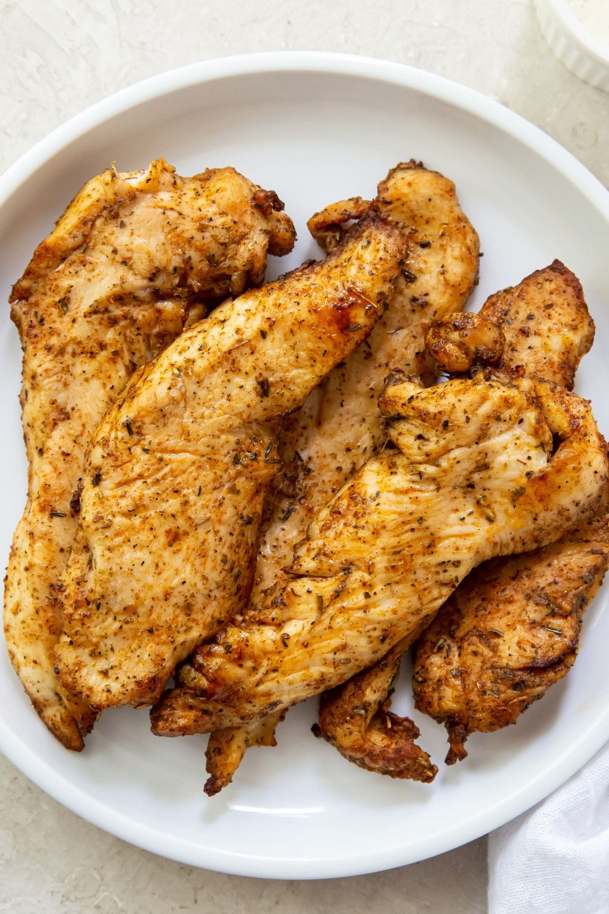 Gray background with white plate chicken breast tenders. 