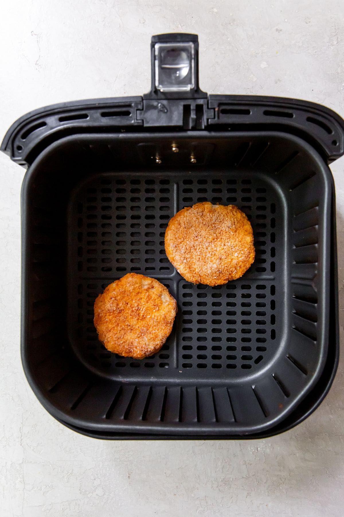 2 chicken patties in a black air fryer