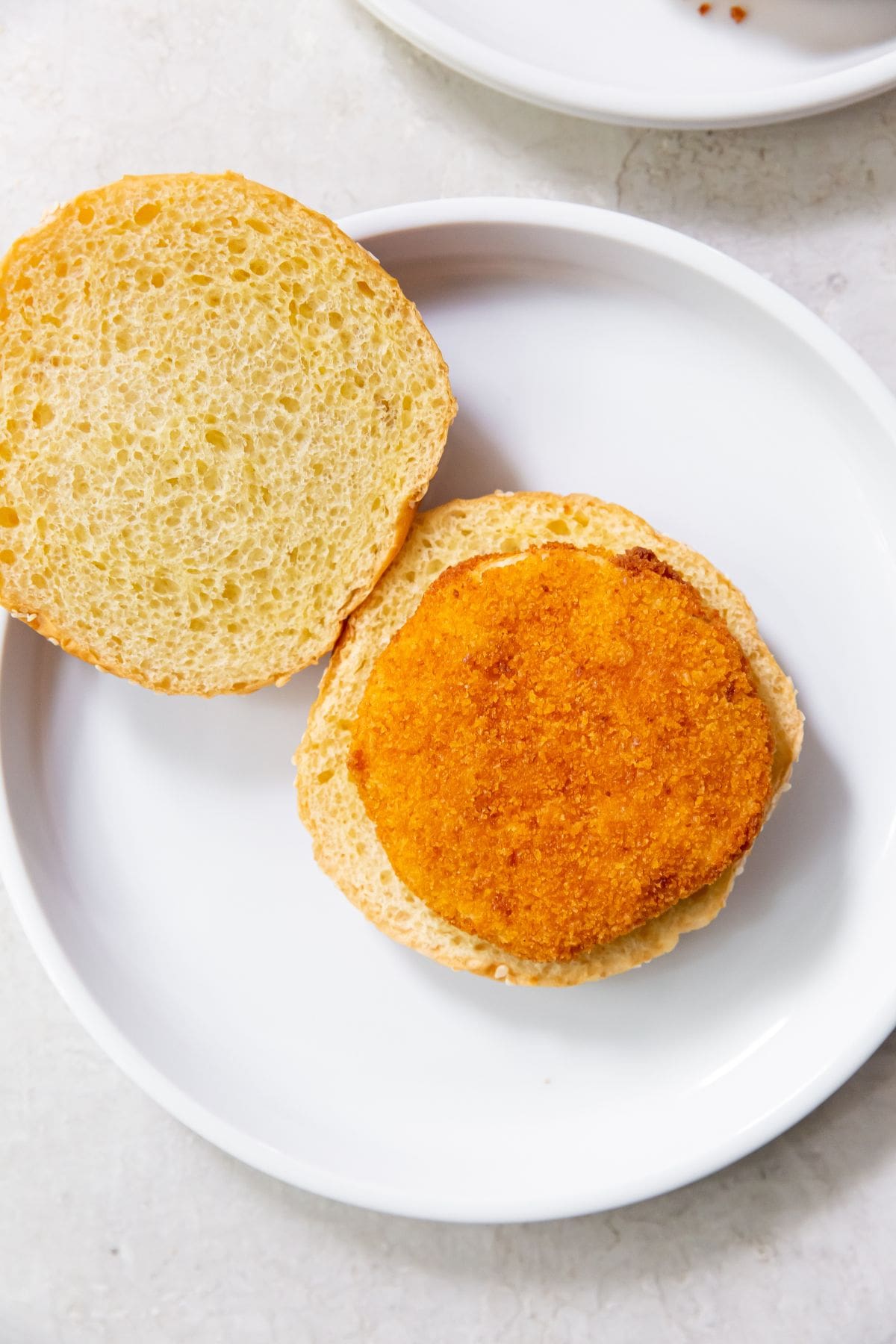 white plate with hamburger bun and chicken patty in the middle