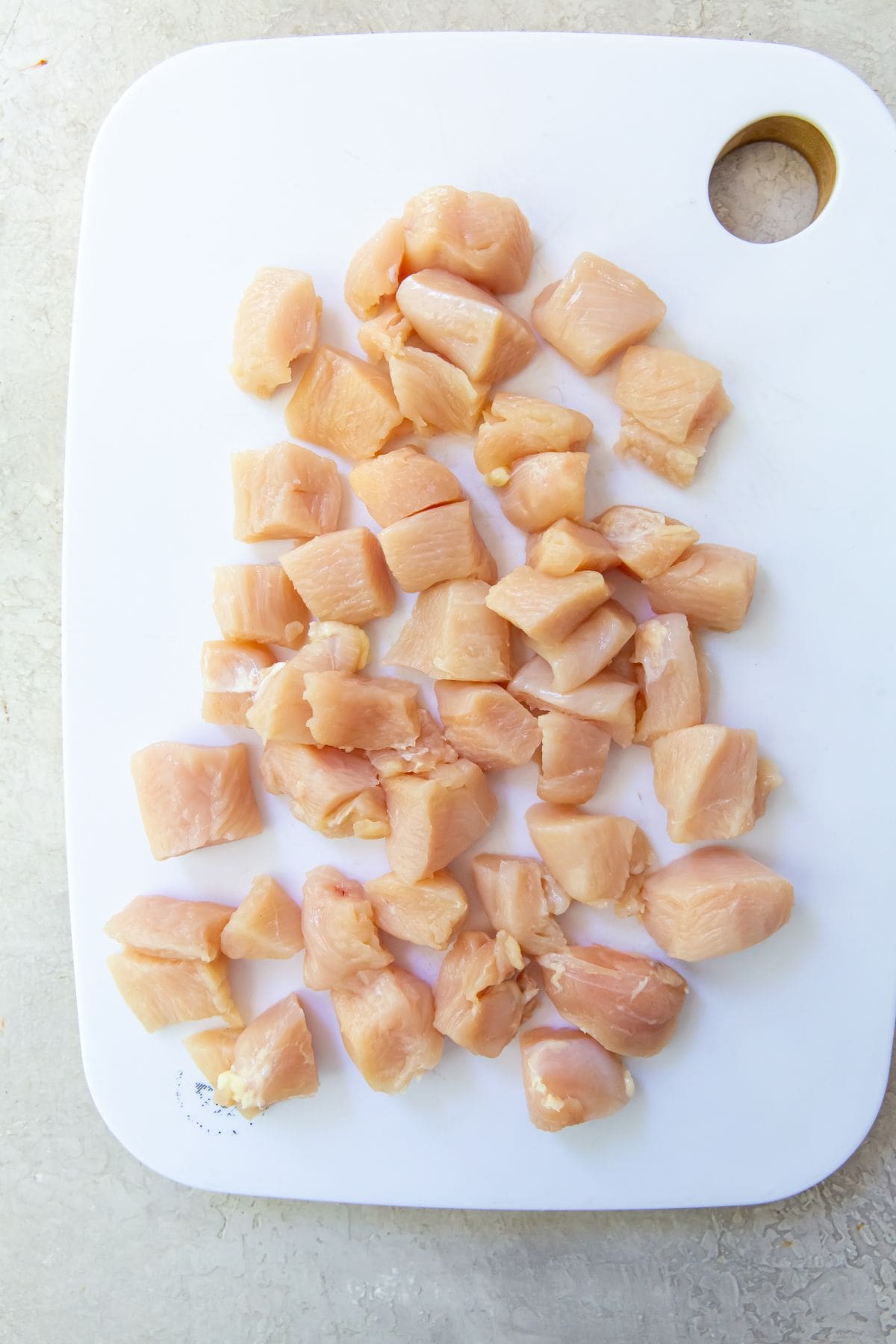 white cutting board with cubed chicken