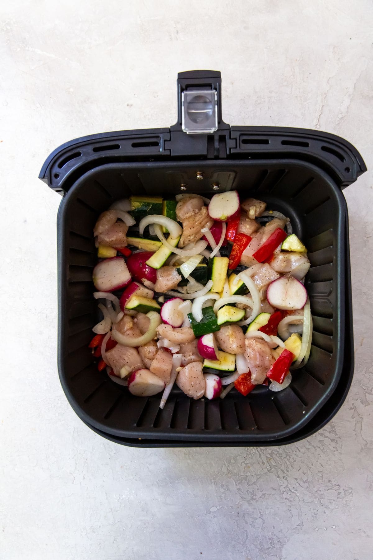 Black Air Fryer with chicken and veggies in it