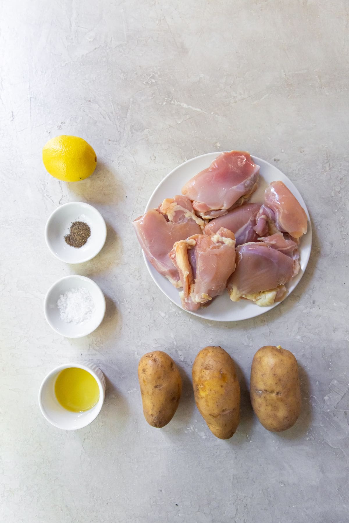 Ingredients for chicken thighs and potatoes (lemon, seasonings, avocado oil, potatoes, and chicken thighs)