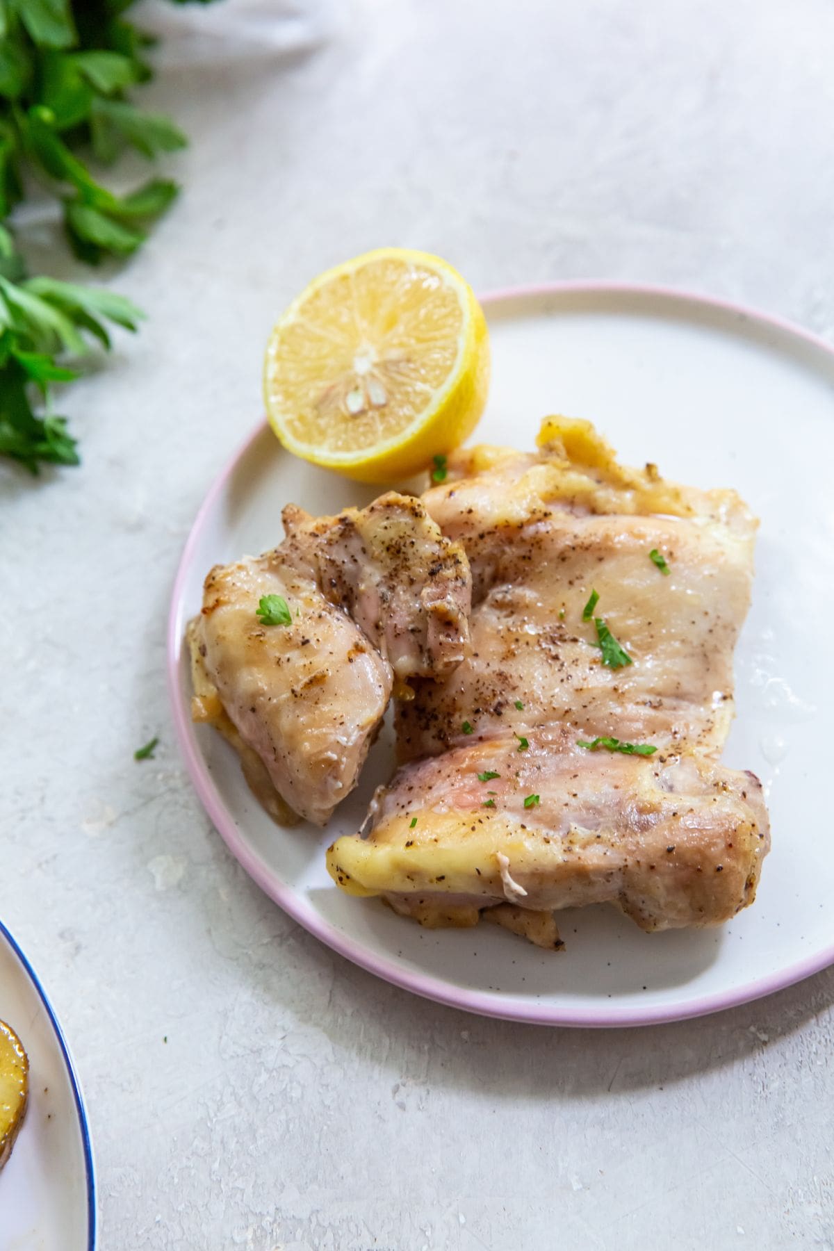 chicken thigh on a plate with a lemon on it