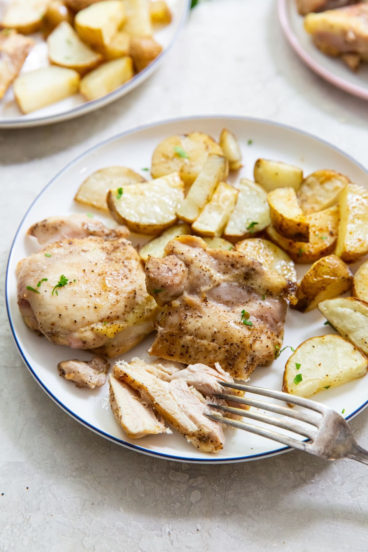 chicken thighs and potatoes on a plate with a fork on the plate