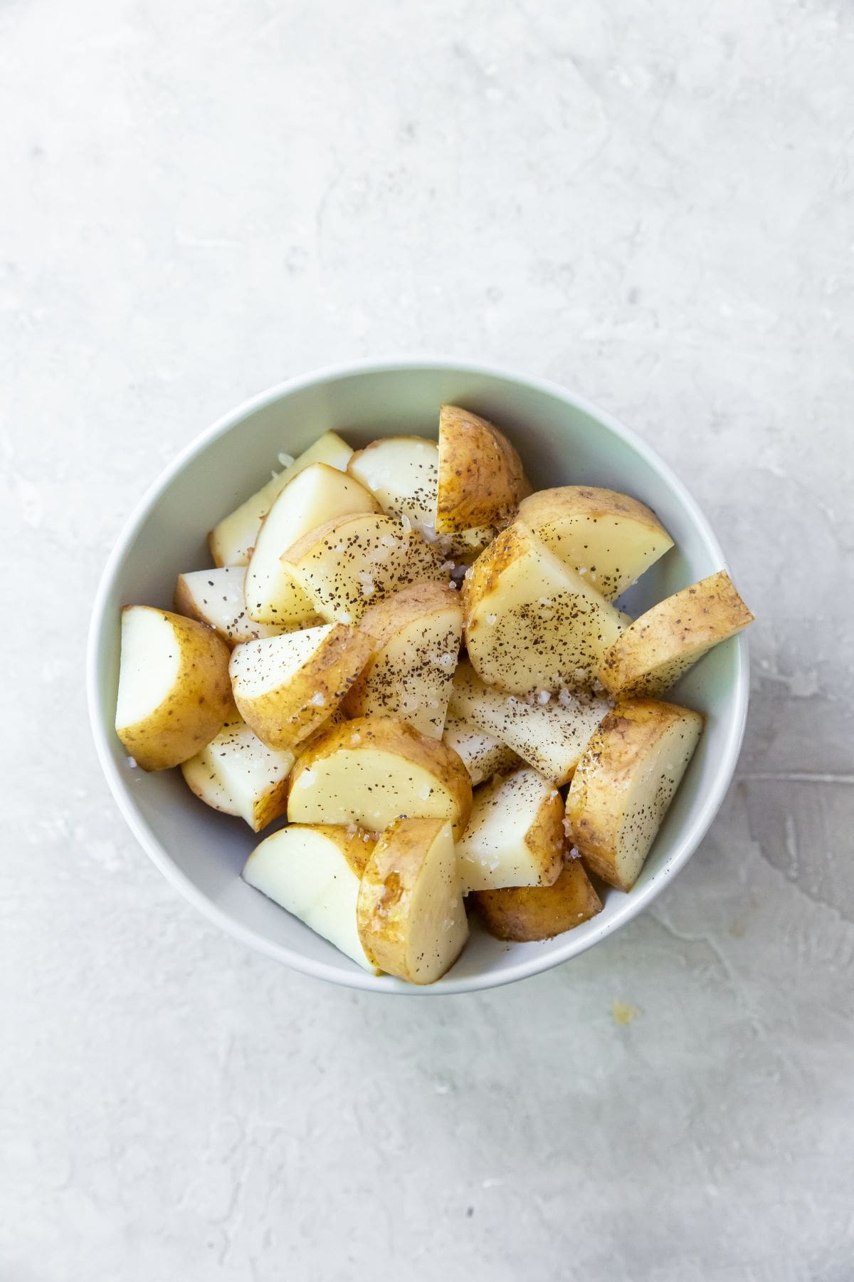 potatoes in a white bowl with seasonings.