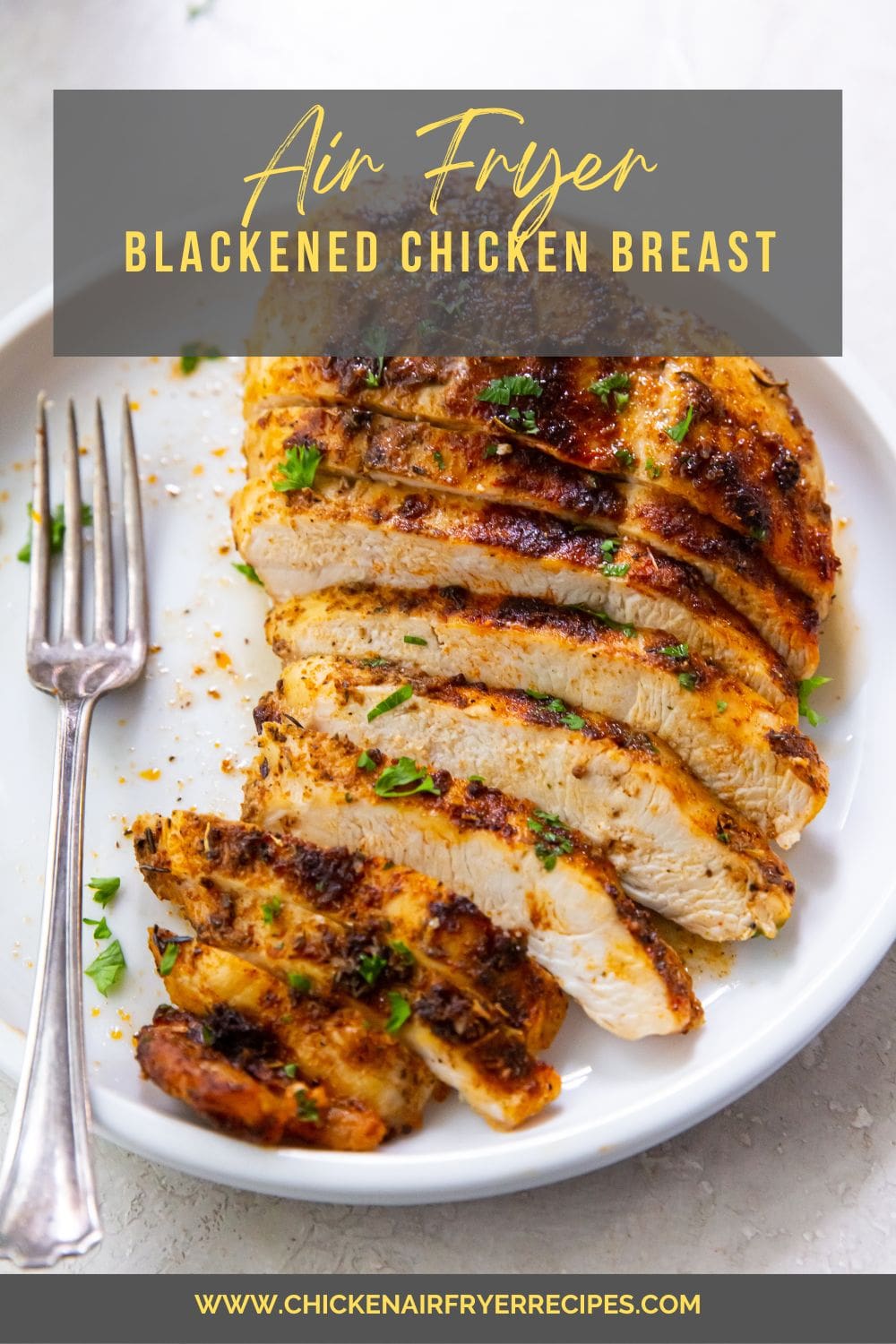 blackened chicken breast cut up on a white plate fork on plate