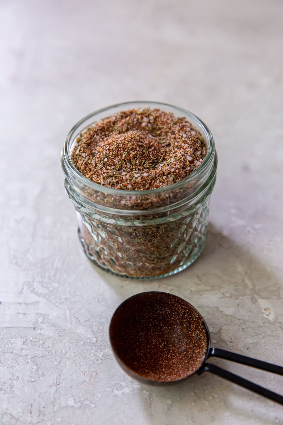 Mason jar with dry rub seasoning inside. Tablespoon in front