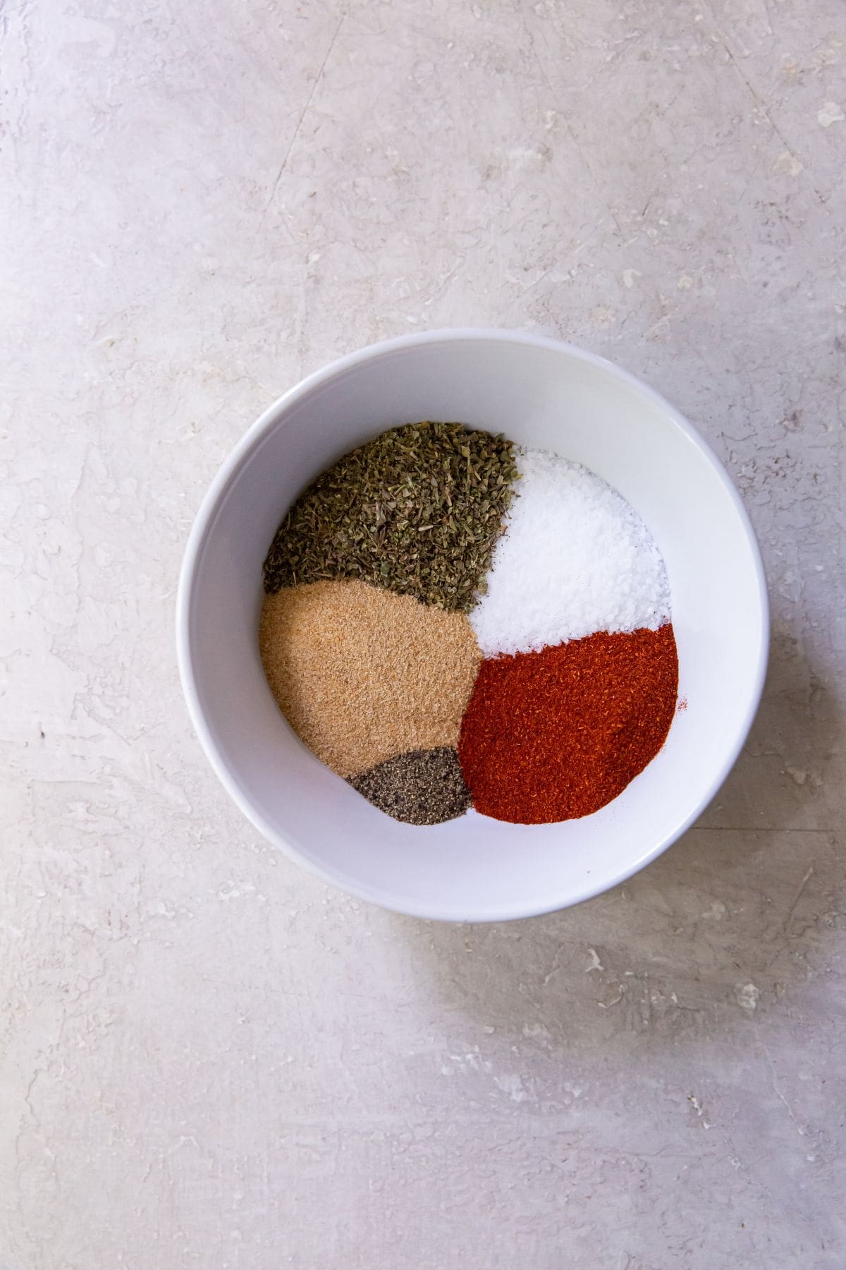 All ingredients in a mixing bowl (salt, garlic, Italian, paprika, pepper)