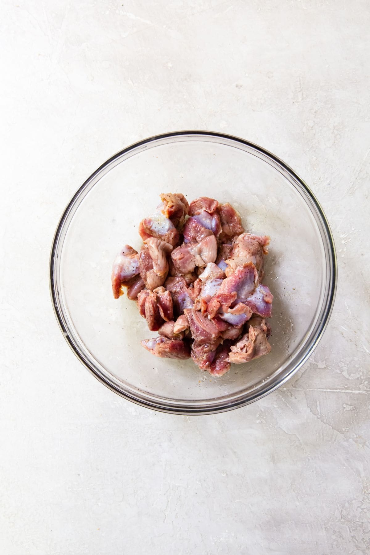 glass bowl with chicken gizzards tossed in seasonings.