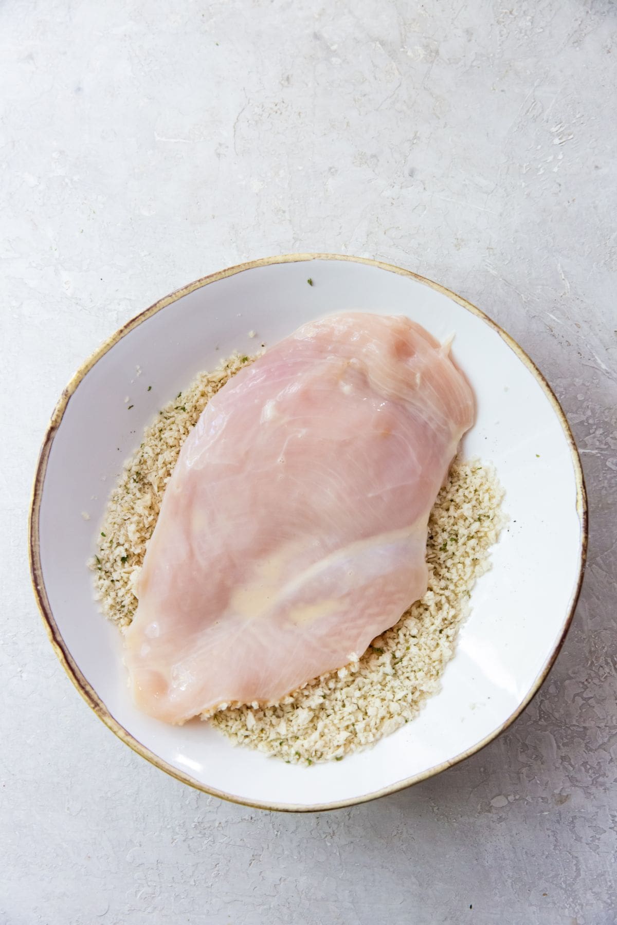 white bowl with chicken breast getting breaded