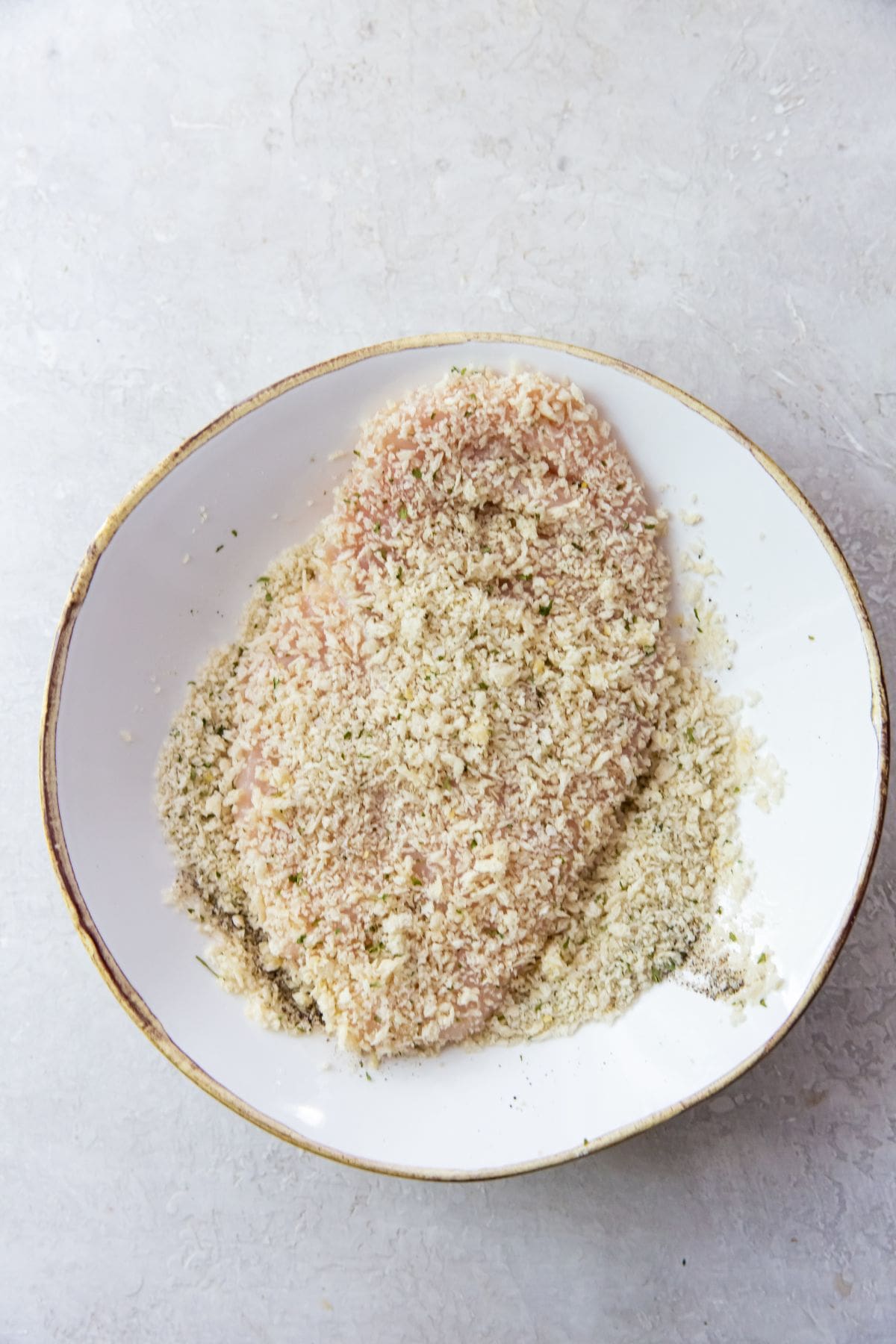 white bowl with chicken breast getting breaded