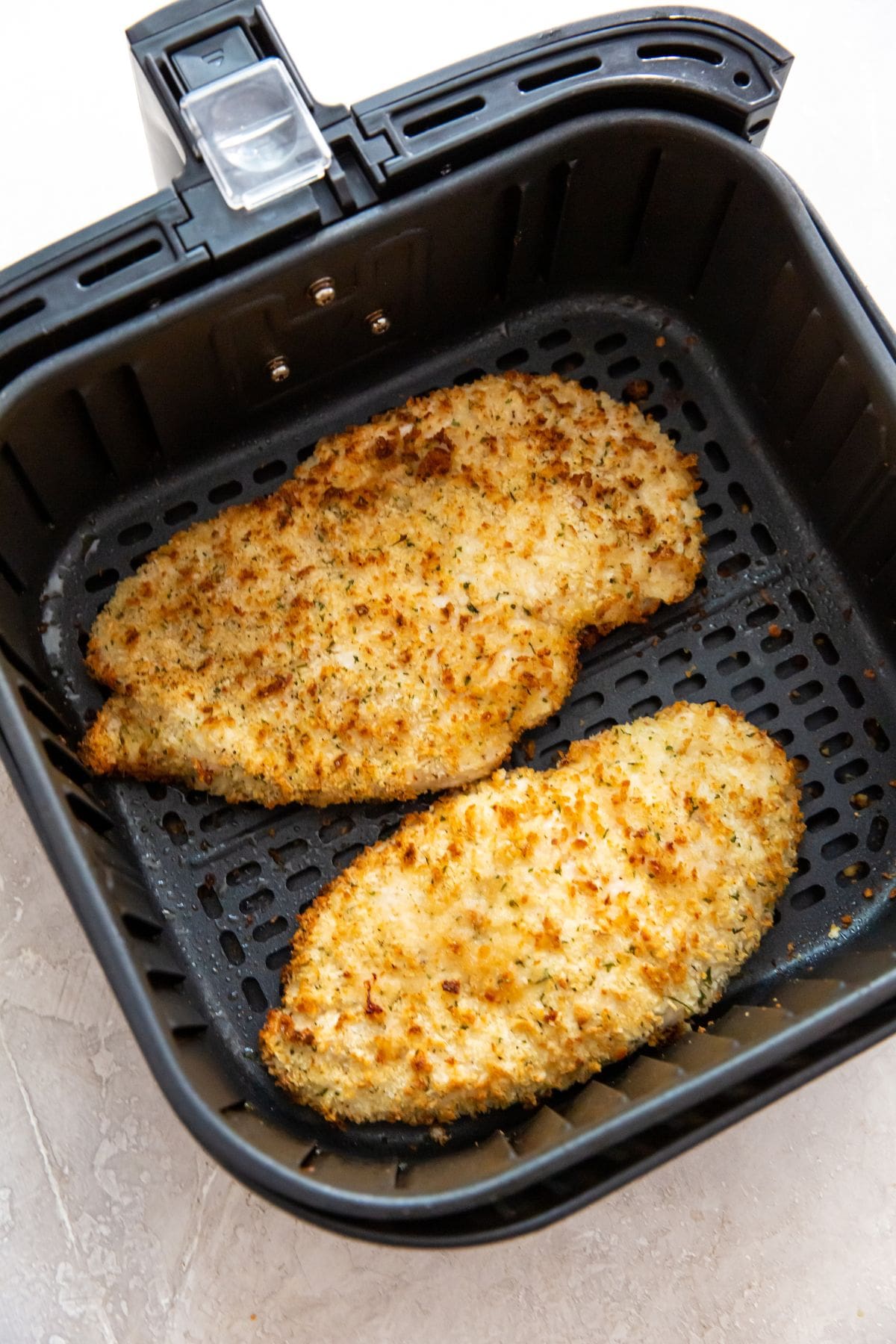 black air fryer with cooked chicken inside