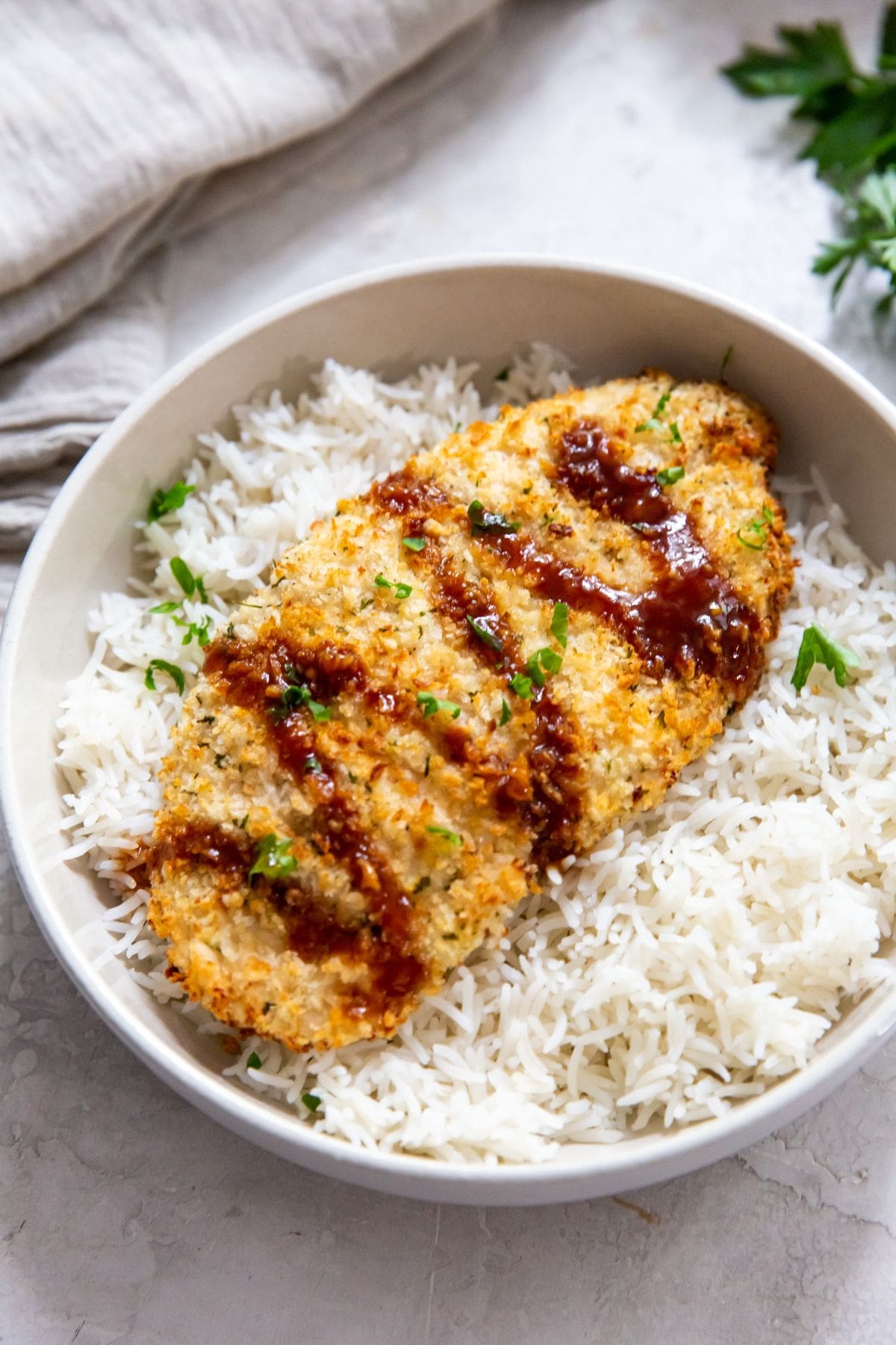 white bowl with air fryer chicken katsu under a bed of rice