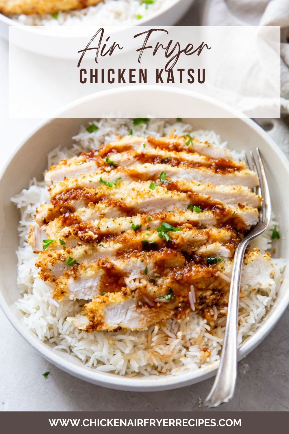 white bowl with air fryer chicken katsu under a bed of rice fork next to it.