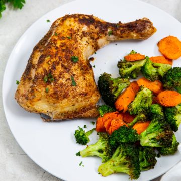 white plate with chicken and vegetables on it parsley in the back. white towel next to it