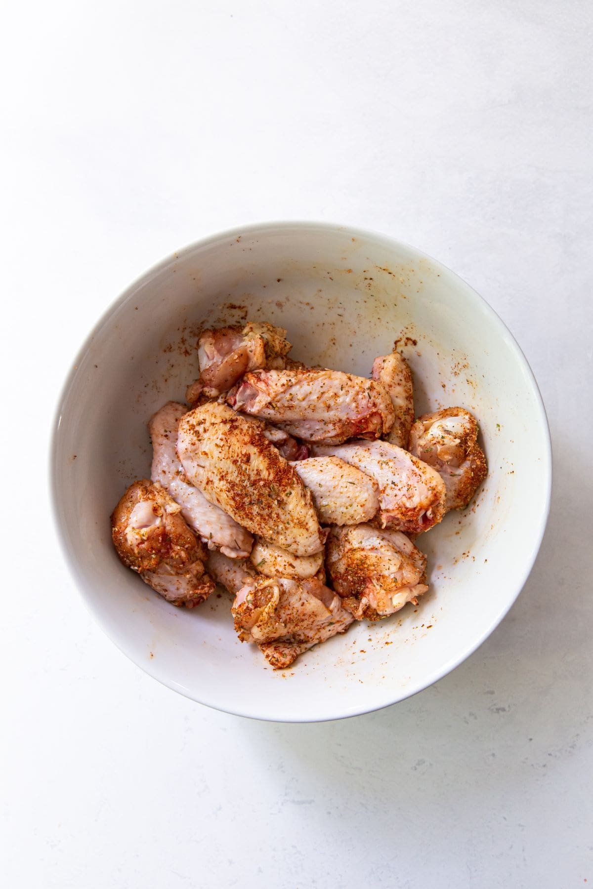 white bowl with chicken wing tossed in dry rub