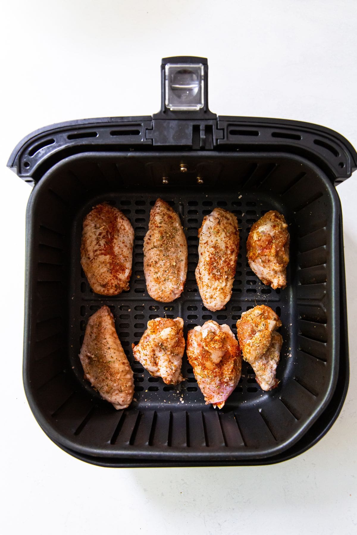 black Air Fryer basket with raw chicken wings inside