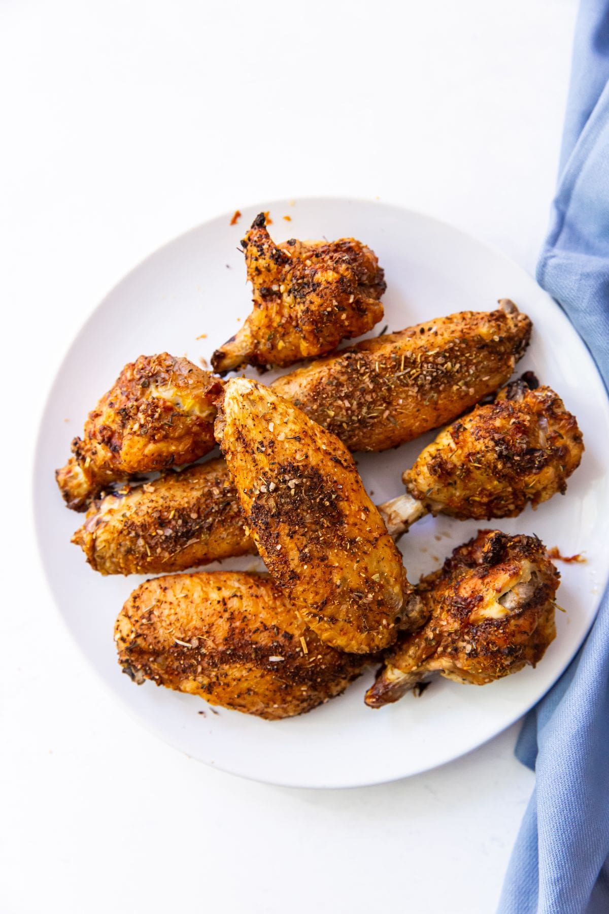 White plate with Air Fryer Chicken Wings with Keto Dry Rub on it. Blue towel next to the plate