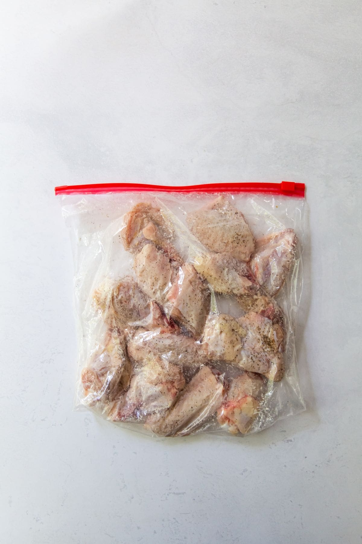 ziplock bag with raw chicken wings tossed in baking soda salt and black pepper