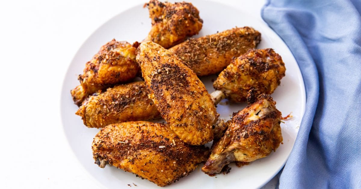 Easy Air Fryer Chicken Wings with Keto Dry Rub, parsley, and a white sauce.