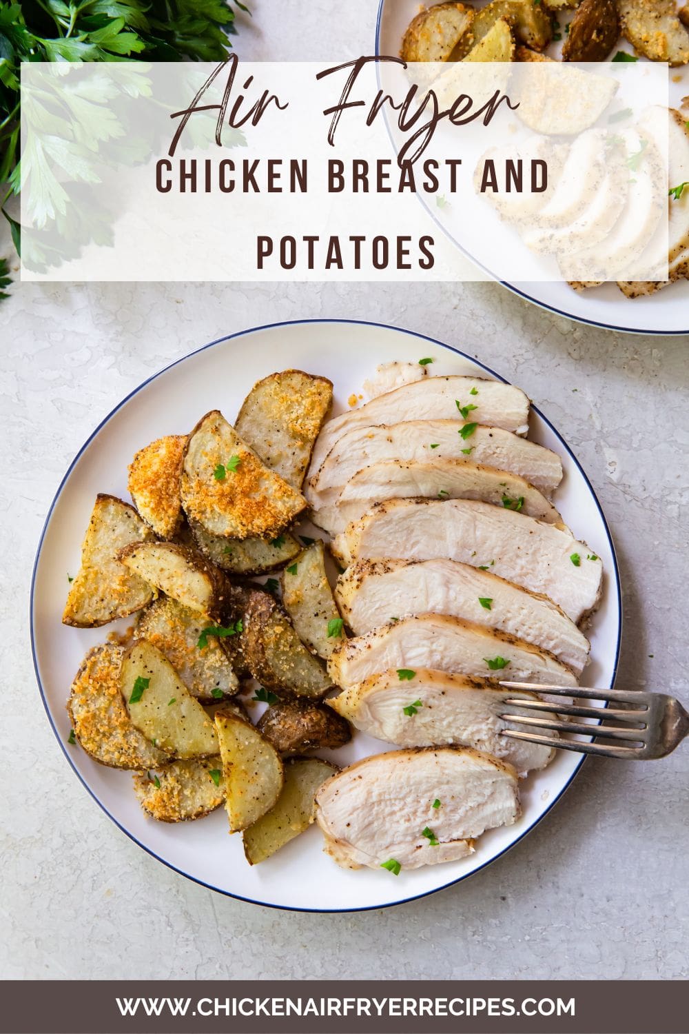 two plates with chicken and potatoes fork on plate parsley in the back