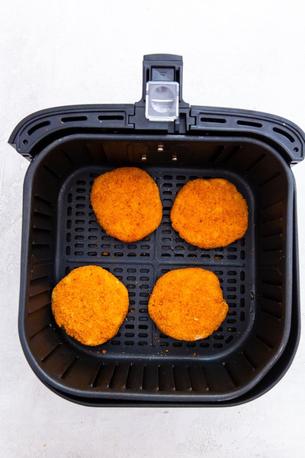 black sir fryer with frozen chicken patties inside