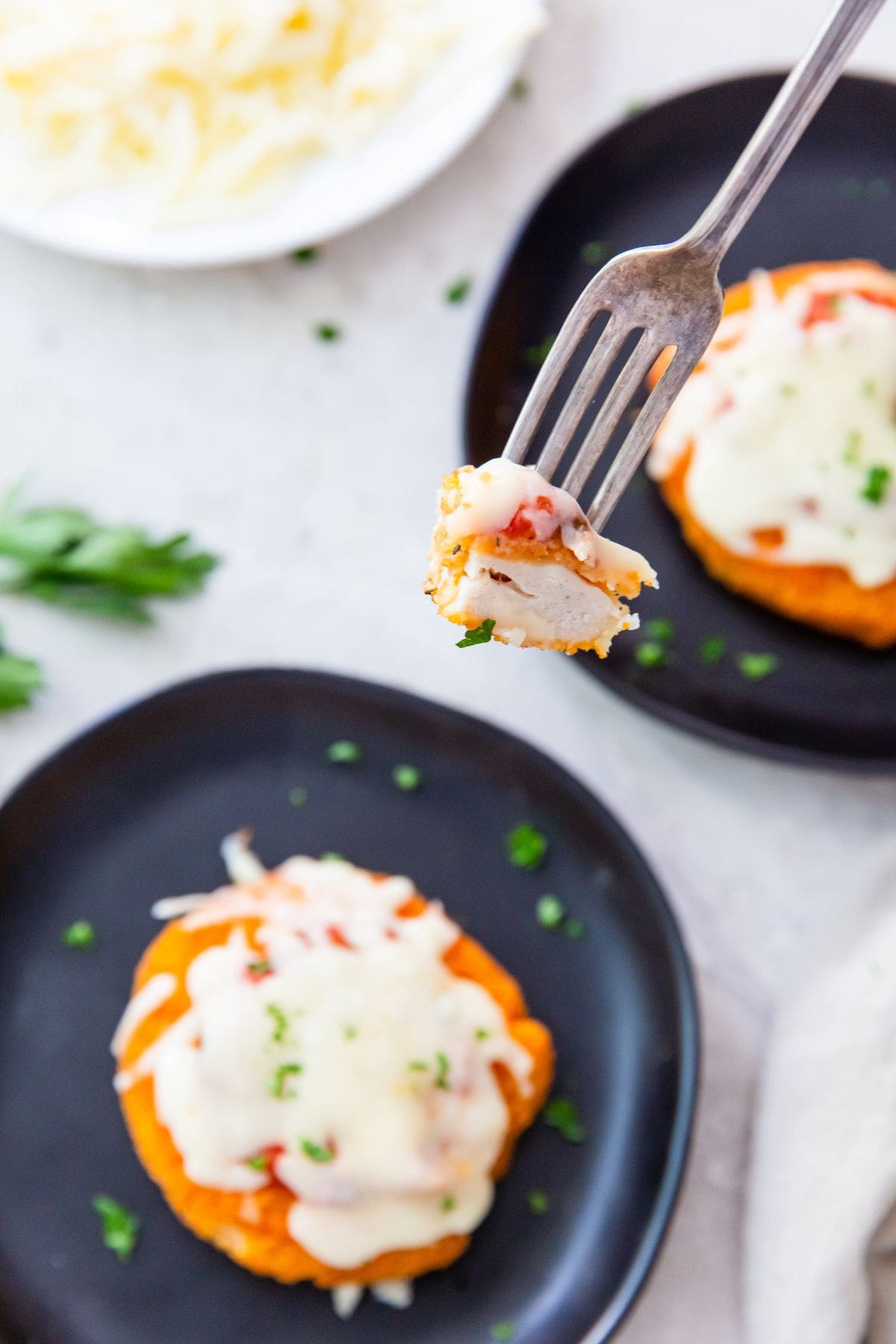 black plates with chicken patties on it a piece being held over the plate with a fork