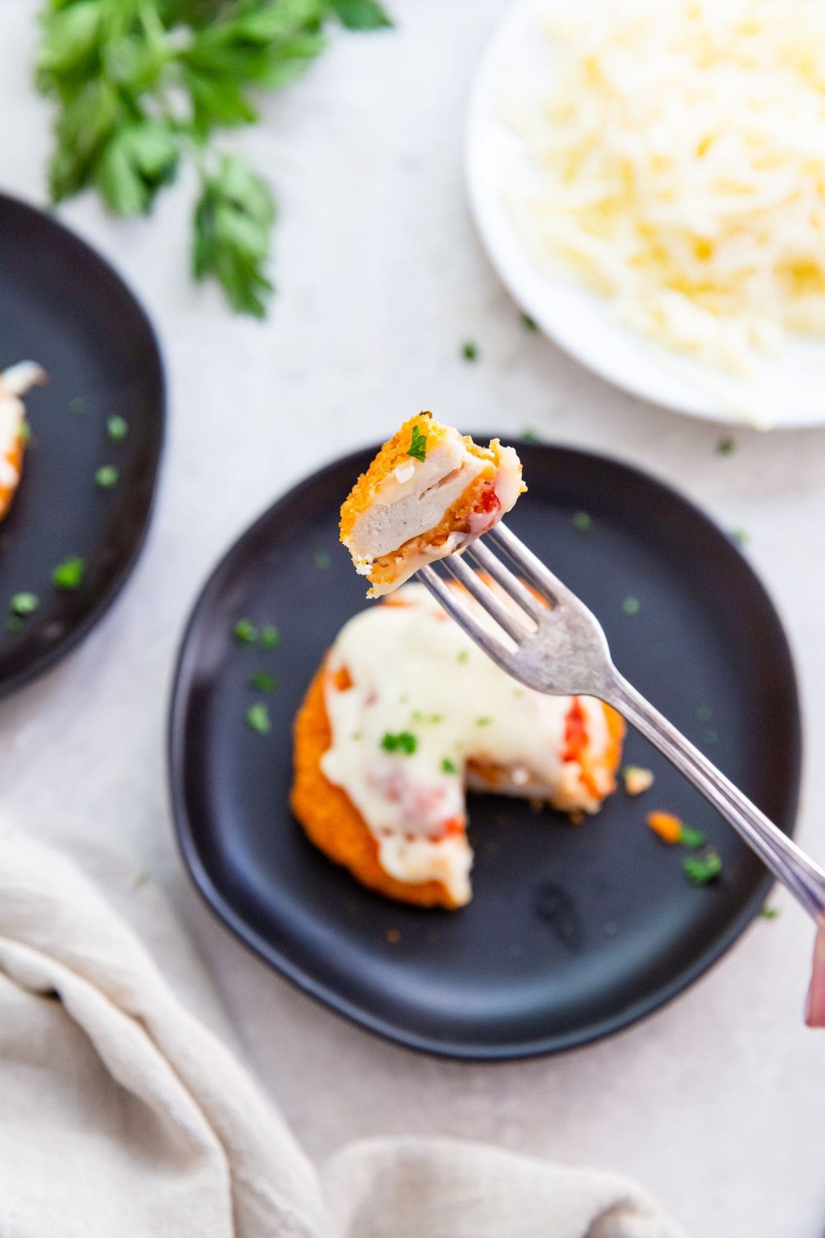 black plates with chicken patties on it a piece being held over the plate with a fork