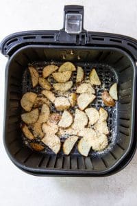 black air fryer with seasoned potatoes inside