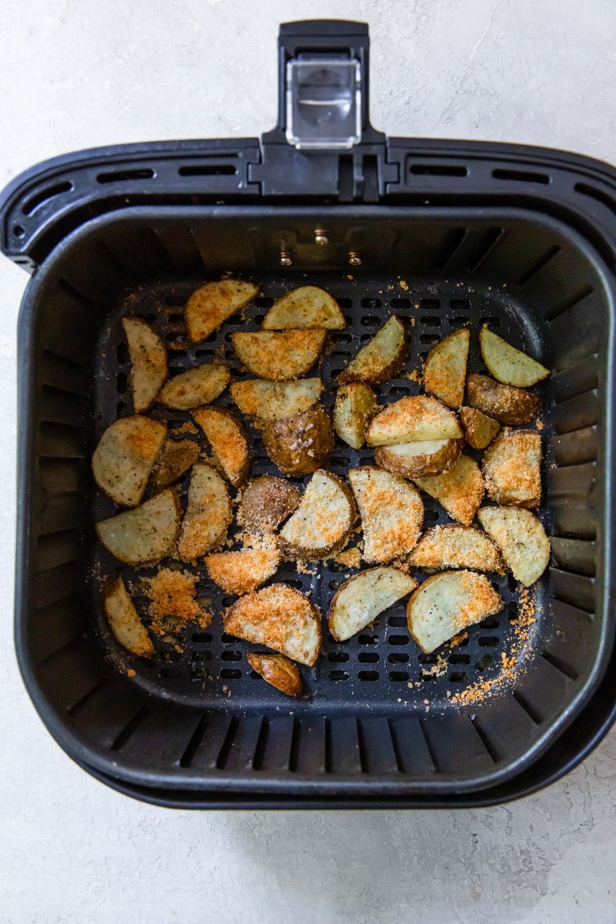 black air fryer with seasoned potatoes