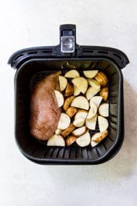 black air fryer with chicken breast and potatoes inside