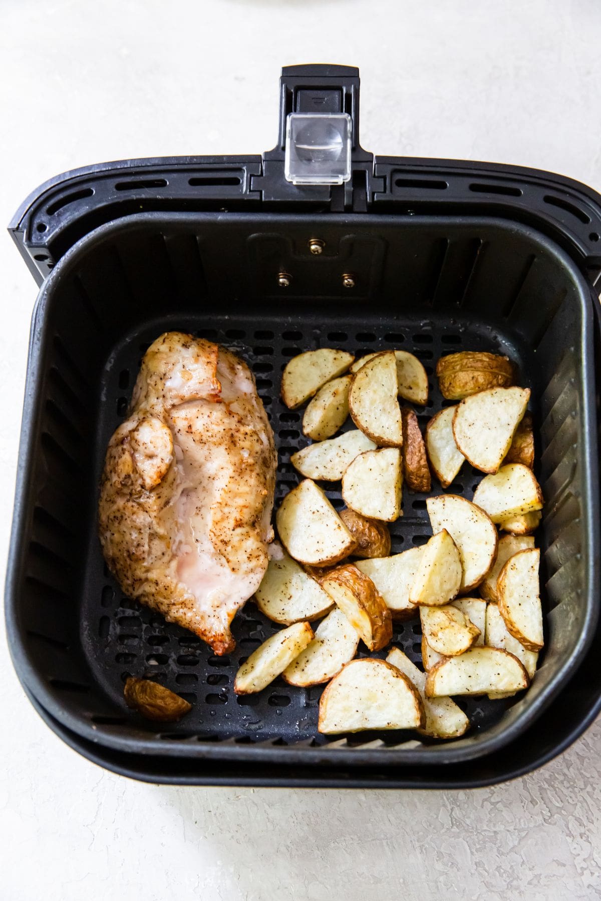 cooked chicken breast and potatoes in an air fryer