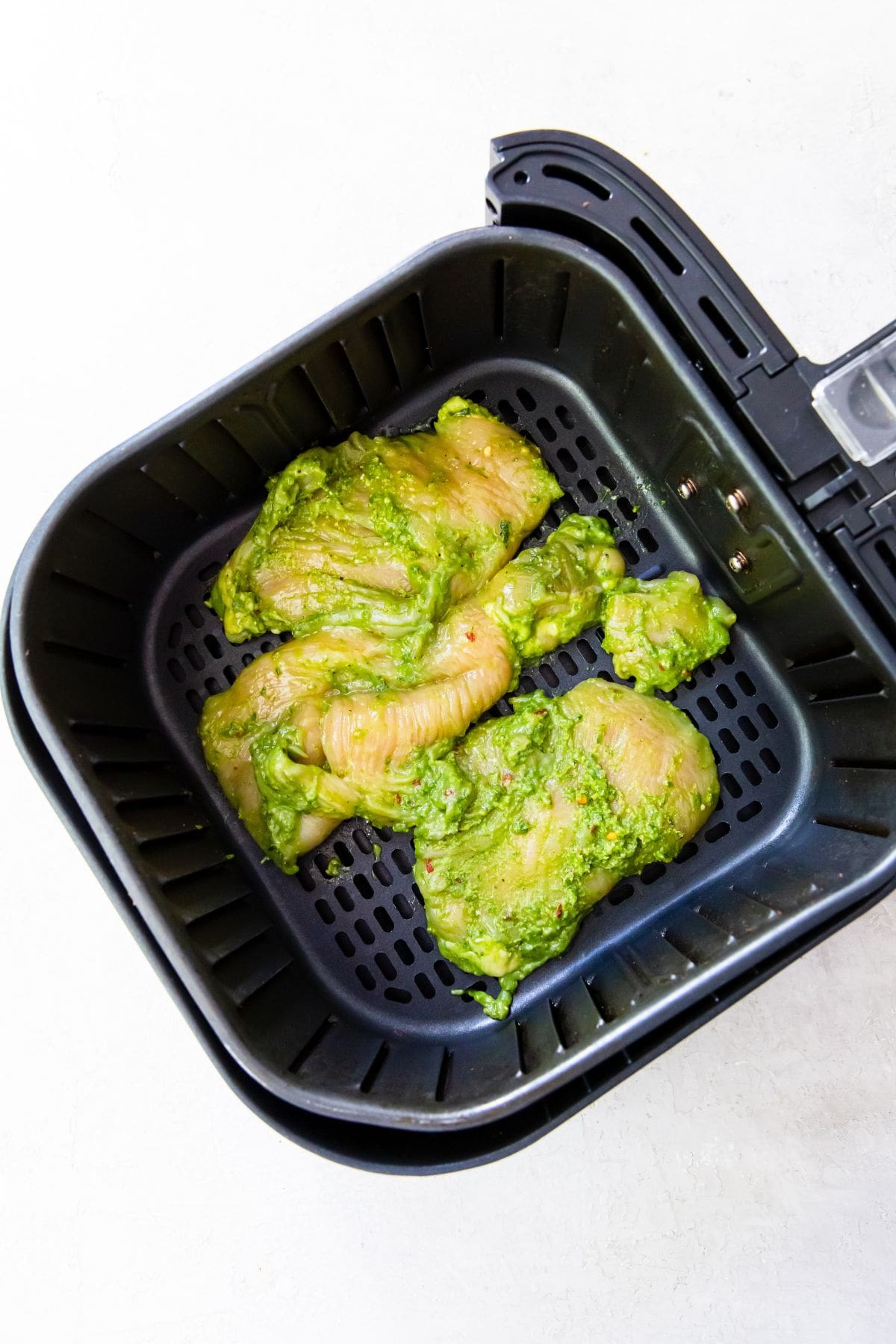 raw chicken in a black air fryer basket