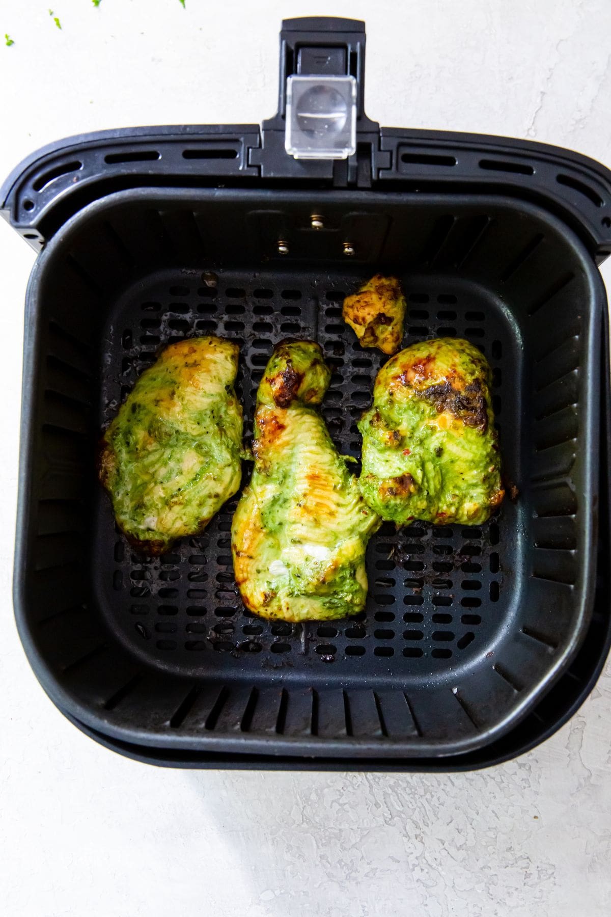 cooked chicken inside a black air fryer basket