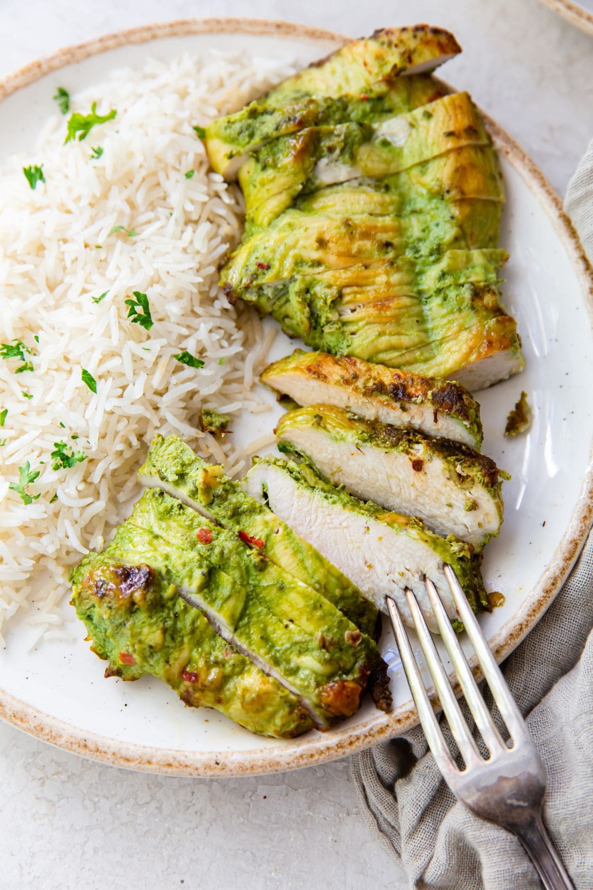 white plate with pesto chicken and rice with a fork