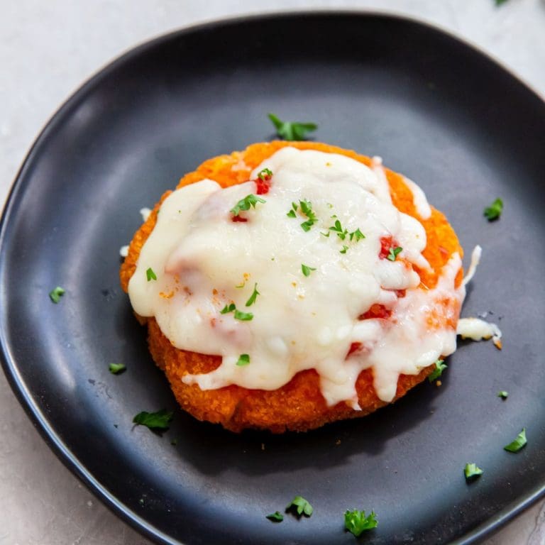 black plates with chicken patty Parm on it