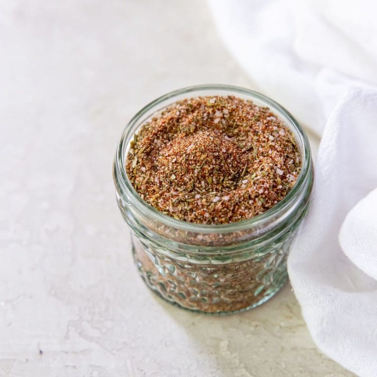 Mason jar with dry rub seasoning inside. White towel on the side