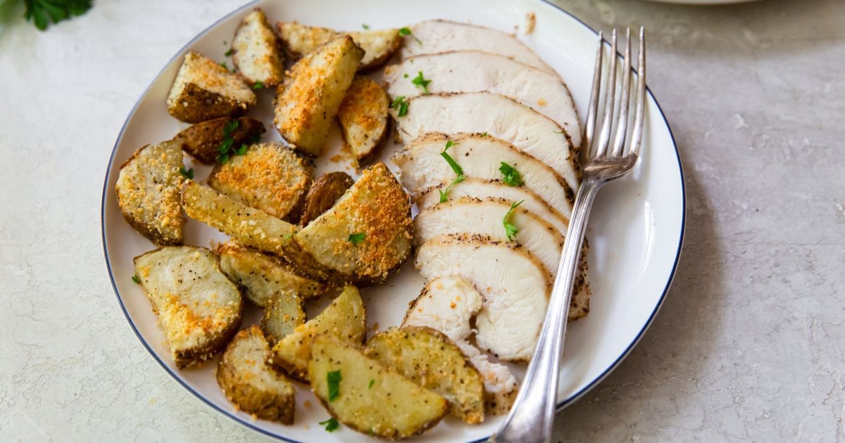 Easy Air Fryer Chicken Breast and Potatoes on a white plate with parsley.