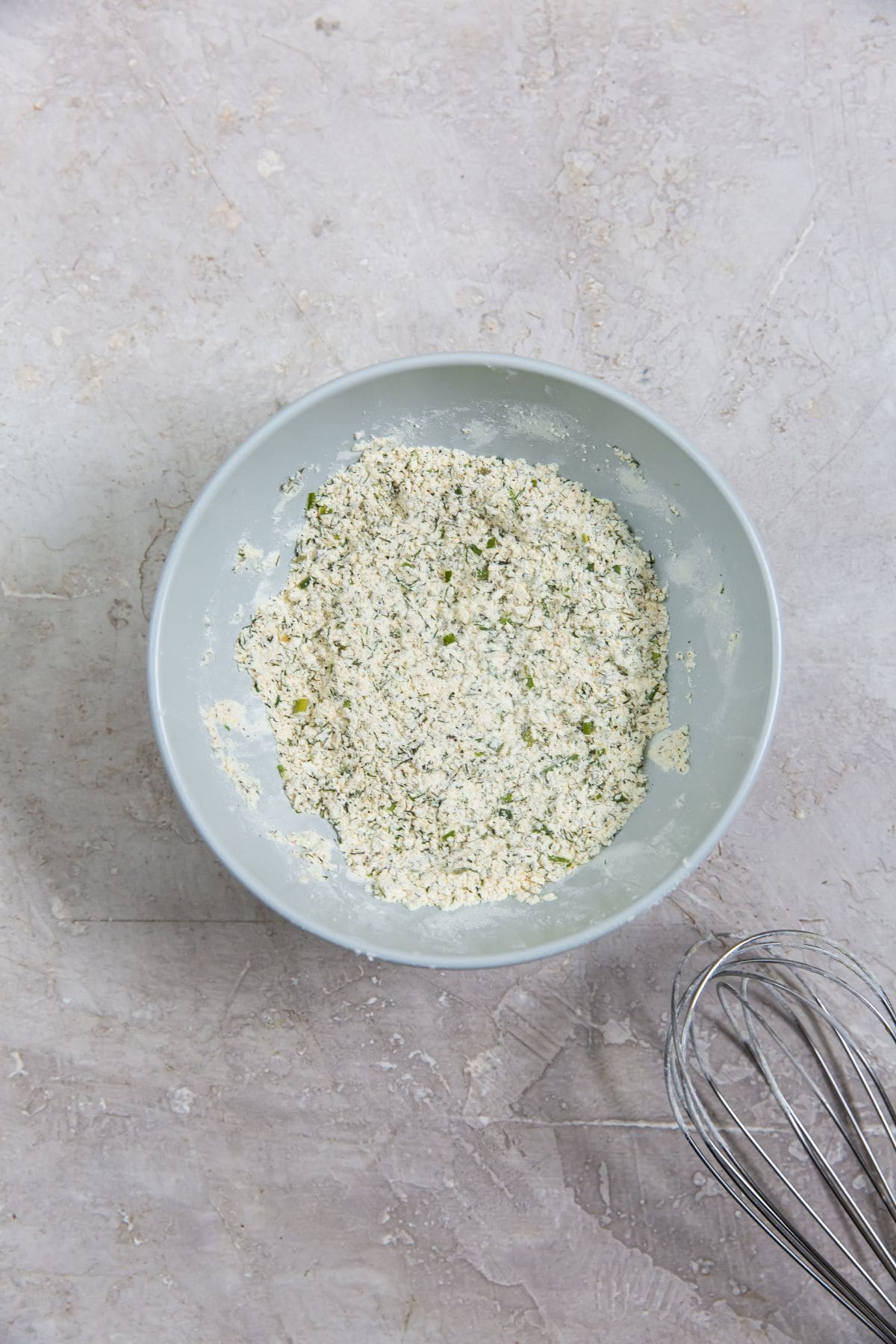 mixing bowl with all the ingredients mixed together. whisk next to it.