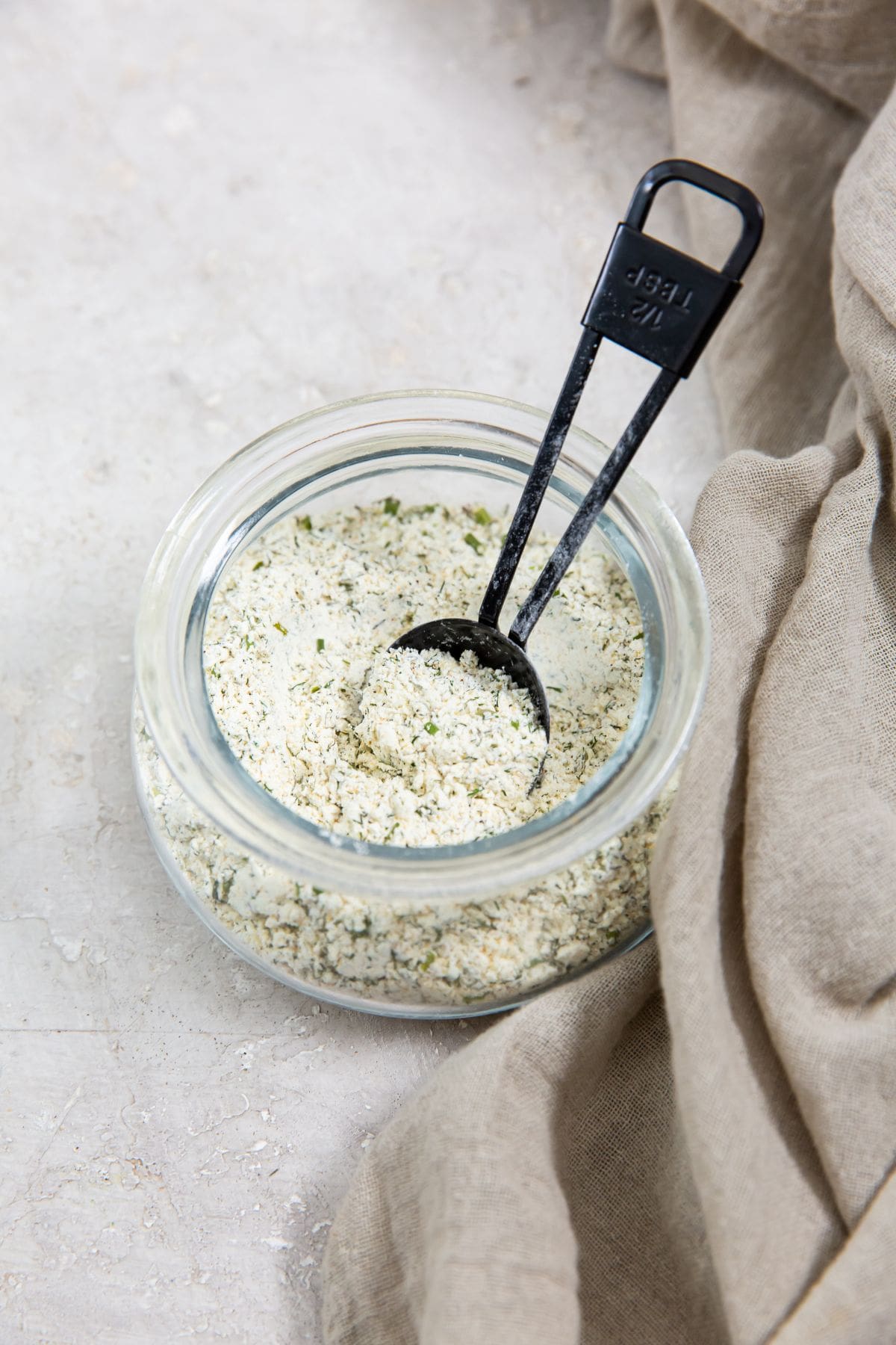 ranch seasoning inside a jar tablespoon inside jar. gray towel next to it