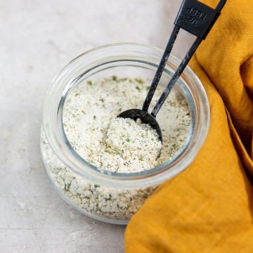 ranch seasoning inside a jar tablespoon inside jar. orange towel next to it