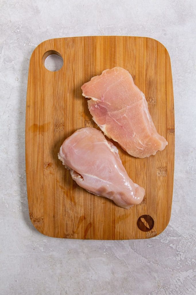 cutting board with chicken breast cut in half