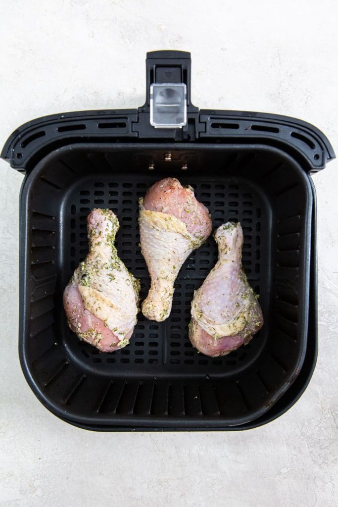 black air fryer with raw chicken inside